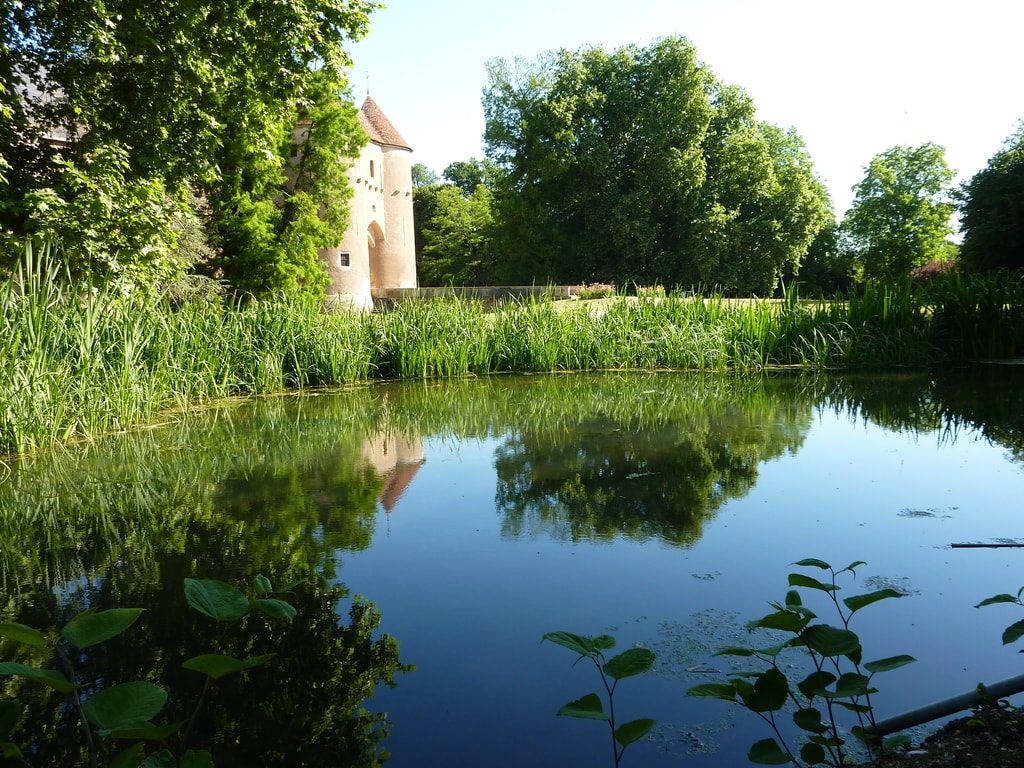 View of the entrance gatehouse of Ainay le Vieil castle behind the pond