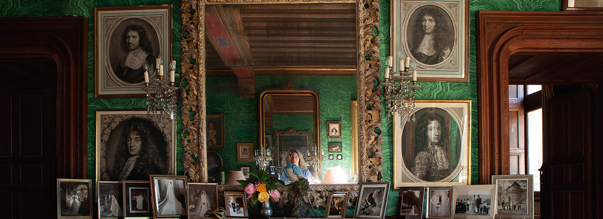 Château d&#039;Ainay-le-Vieil, Colbert salon with framed portraits above a bookcase filled with leather-bound books