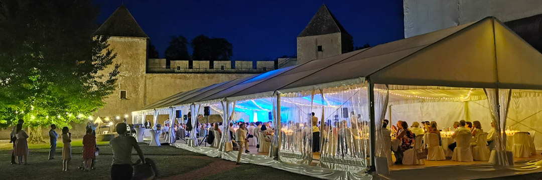 Château d'Ainay-le-Vieil, réception dans la cour du château sous tente de réception avec parquet, éclairages