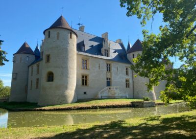 Château d'Ainay-le-Vieil, vue du Logis Renaissance et des douves par grand soleil, ciel bleu