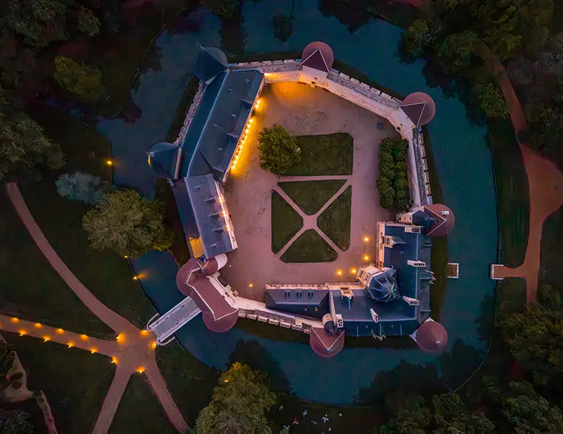 Le château d'Ainay-le-Vieil, vue par drone, illuminé à la tombée de la nuit